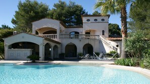 Une villa de style méditerranéen dotée d’une piscine, d’arcades et d’un balcon donnant sur la piscine.