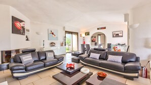 Ein modernes Wohnzimmer mit zwei schwarzen Ledersofas, einem Glastisch und einem Kamin.
