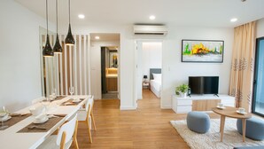 A modern living room with a dining area, a TV, and a painting on the wall. - Republic Plaza Serviced Apartment (Ho Chi Minh City)