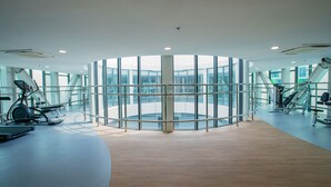 A modern gym with a circular layout, large windows, and various exercise equipment. - Republic Plaza Serviced Apartment (Ho Chi Minh City)