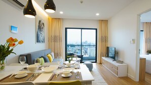 A modern living room with a dining area, a sofa, a TV, and a view of the city. - Republic Plaza Serviced Apartment (Ho Chi Minh City)