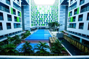A modern hotel with a central courtyard featuring a swimming pool, surrounded by lush greenery and palm trees. - Republic Plaza Serviced Apartment (Ho Chi Minh City)