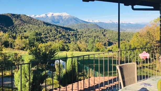 Un balcón con vistas a una cadena montañosa y un valle boscoso.