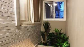 A narrow stairwell with a brick wall and a window. - U Guesthouse 2 in Yeonnam Caters to Women - Hostel (Seoul)