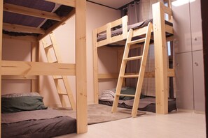 Ein Schlafraum mit Etagenbetten, einer Leiter, Holzwänden und einem Kleiderschrank.