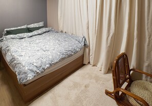 Ein Schlafzimmer mit einem Bett, einem Sessel und Vorhängen.