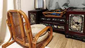 A wicker chair with a woven seat and backrest, positioned on a light-colored rug. - U Guesthouse 2 in Yeonnam Caters to Women - Hostel (Seoul)