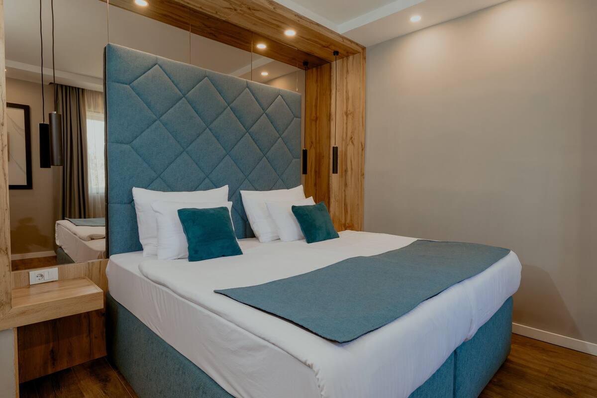 A modern bedroom with a large bed, a wooden headboard, and a bedside table.