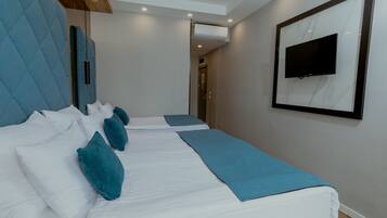 Habitación de hotel con dos camas, un televisor montado en la pared e iluminación empotrada en el techo.