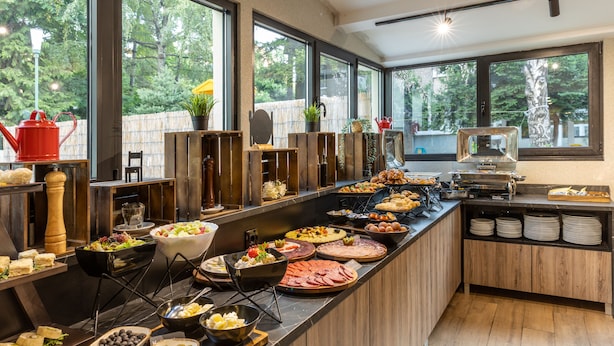 A buffet with various food items and a view of the outdoors through large windows. - Nobel Gallery Hotel (Belgrade)