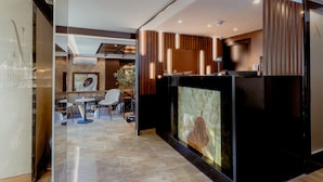 A modern hotel lobby with a reception desk, seating area, and a large artwork on the wall. - Nobel Gallery Hotel (Belgrade)