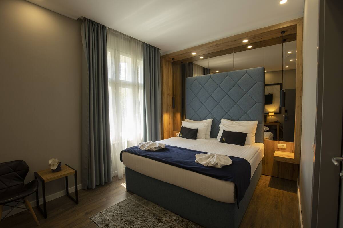 A modern hotel room with a large bed, a small table, and a chair.