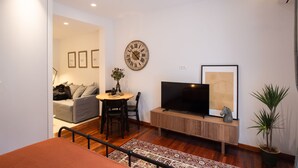 A modern living room with a sofa, dining table, TV, and decorative items. - Phaedrus Living: City Luxury Flat Mavromichali (Athens)