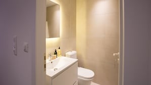 A modern bathroom with a white sink, mirror, and toilet. - Phaedrus Living: City Luxury Flat Mavromichali (Athens)