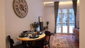 A dining area with a round table, chairs, and a large wall clock. - Phaedrus Living: City Luxury Flat Mavromichali (Athens)