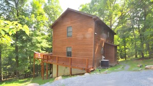 A two-story wooden cabin with a deck, surrounded by trees. - Almost Heaven - Cozy and Wonderful (Berkeley Springs)