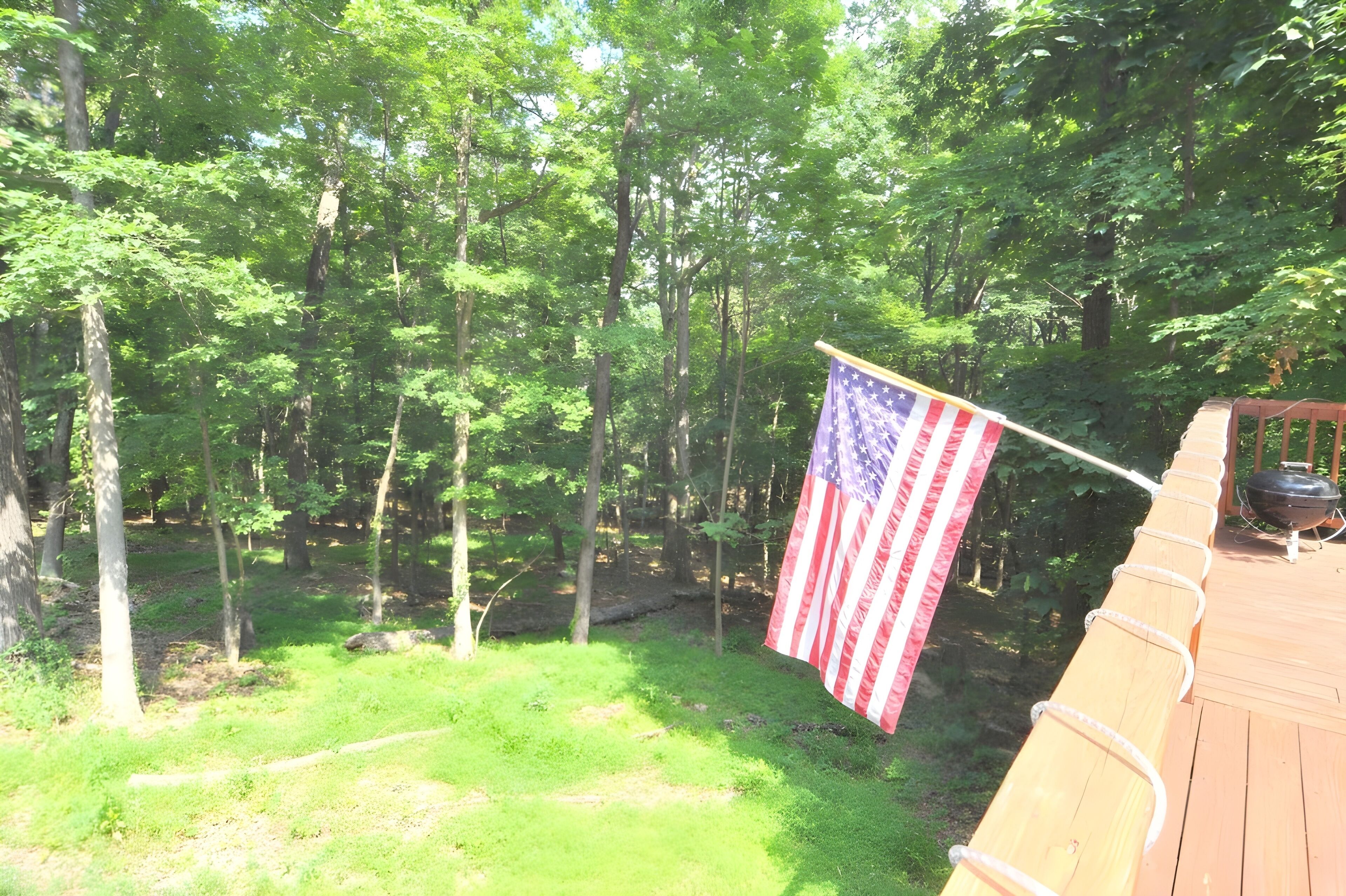 A wooden deck with a flagpole displaying an American flag.
