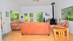 A spacious living room with a large orange sofa, a wooden chair, and a fireplace. - Almost Heaven - Cozy and Wonderful (Berkeley Springs)