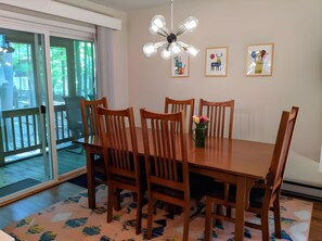 A dining area with a wooden table and chairs, a chandelier, and artwork on the wall.