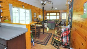 L’intérieur chaleureux d’un chalet avec des murs en bois, un coin repas, un salon doté d’un canapé et de fauteuils, et un espace cuisine.
