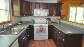Une cuisine de taille réduite, avec des meubles de rangement en bois foncé, une cuisinière blanche, un four à micro-ondes et un grille-pain.
