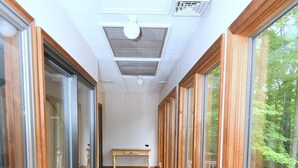 A corridor with wooden flooring, large glass doors, and a bench in the center. - Dogwood Knoll - Wooded Escape (Berkeley Springs)