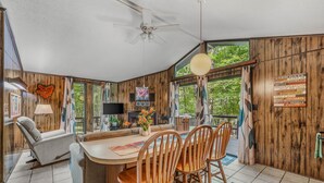 A cozy cabin interior with a wooden interior, a dining area with wooden chairs, a ceiling fan, and a view of the outdoors. - Country Comfort -country Escape! (Hedgesville)