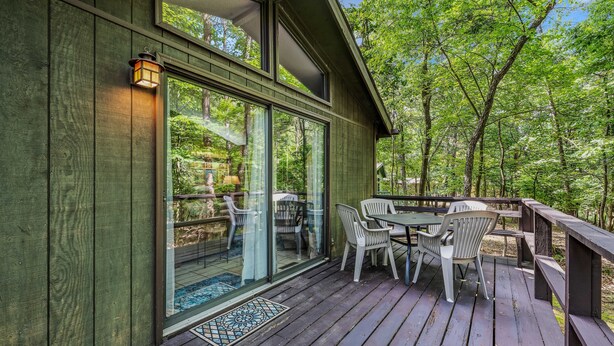 A wooden deck with outdoor furniture and a glass door leading to a patio area. - Country Comfort -country Escape! (Hedgesville)