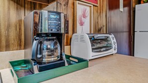A coffee maker on a green tray, a toaster oven, and a wooden wall with a 'KITCHEN' sign. - Country Comfort -country Escape! (Hedgesville)