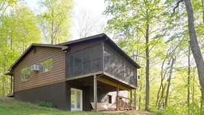 A two-story house with a large deck and a fire pit in the front yard.