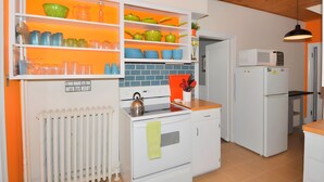 A kitchen with white cabinets, a stove, a microwave, and a sink. - Aunt Beas Bungalow - Right in Town! (Berkeley Springs)