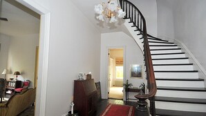 A staircase with a wooden handrail and black steps, leading to a room with a red rug and a small plant. - Manor at Berkeley Springs (Berkeley Springs)