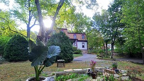 A garden with a stone pathway leading to a house with a red roof. - Manor at Berkeley Springs (Berkeley Springs)