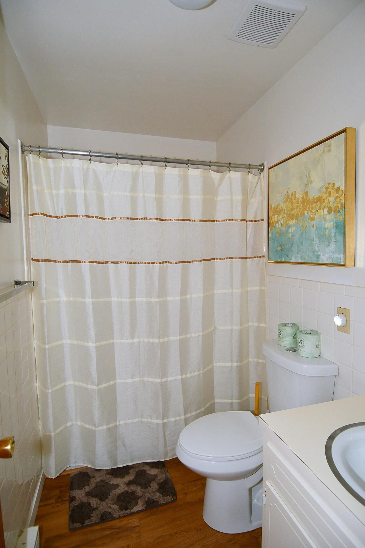 A bathroom with a shower curtain, toilet, and sink.