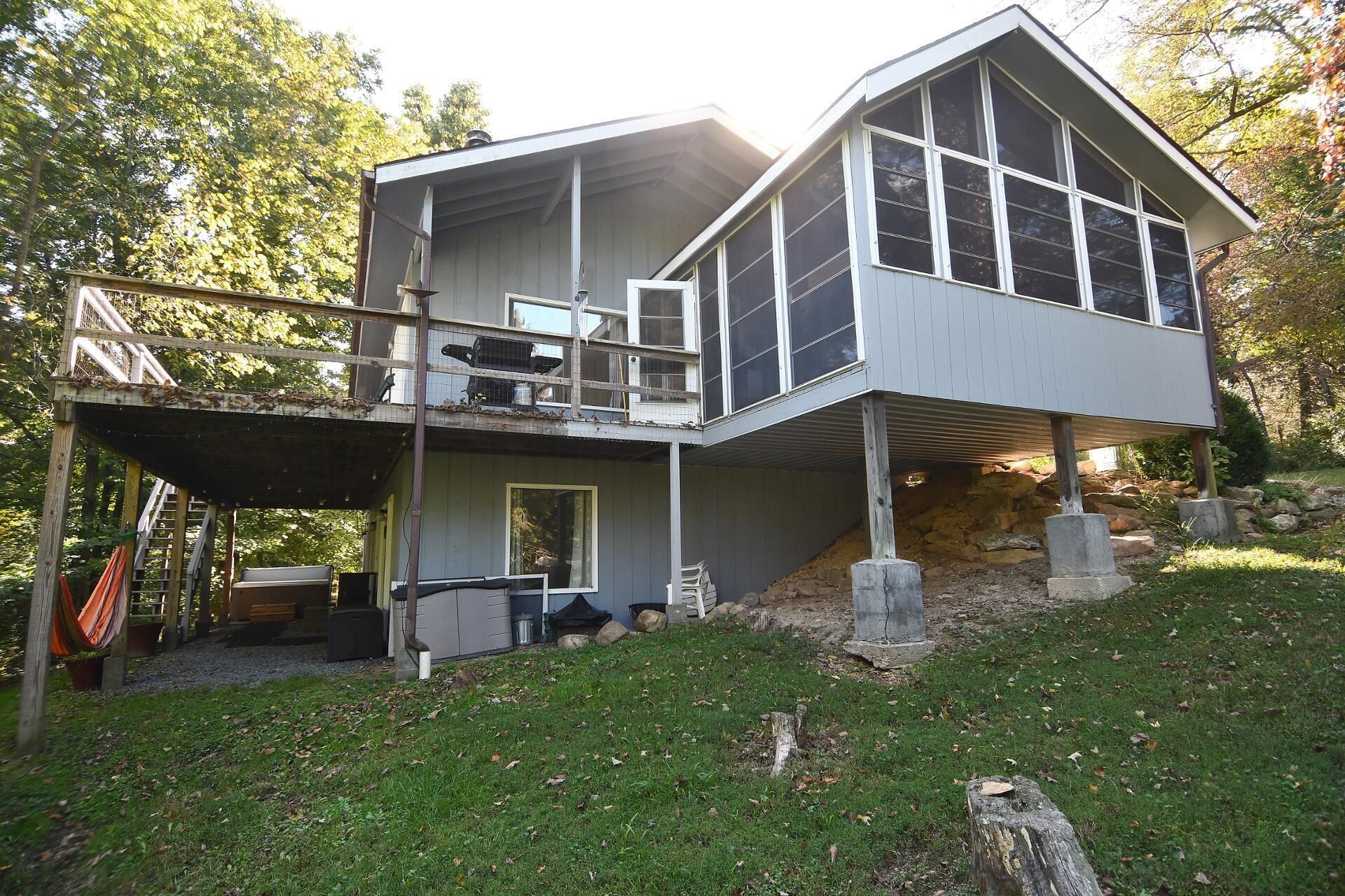 A two-story house with a balcony, a covered patio, and a stone foundation.