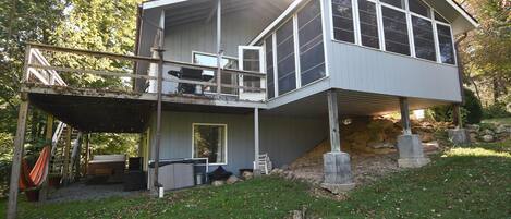 A two-story house with a balcony, a covered patio, and a stone foundation.