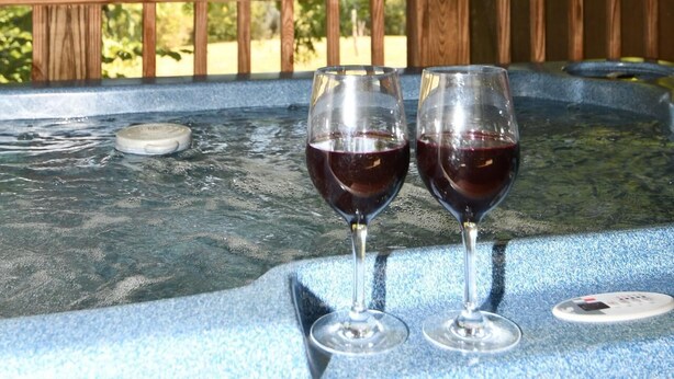 Two glasses of red wine on a blue surface with a wooden railing in the background. - Whispering Hills - Couples Getaway (Berkeley Springs)
