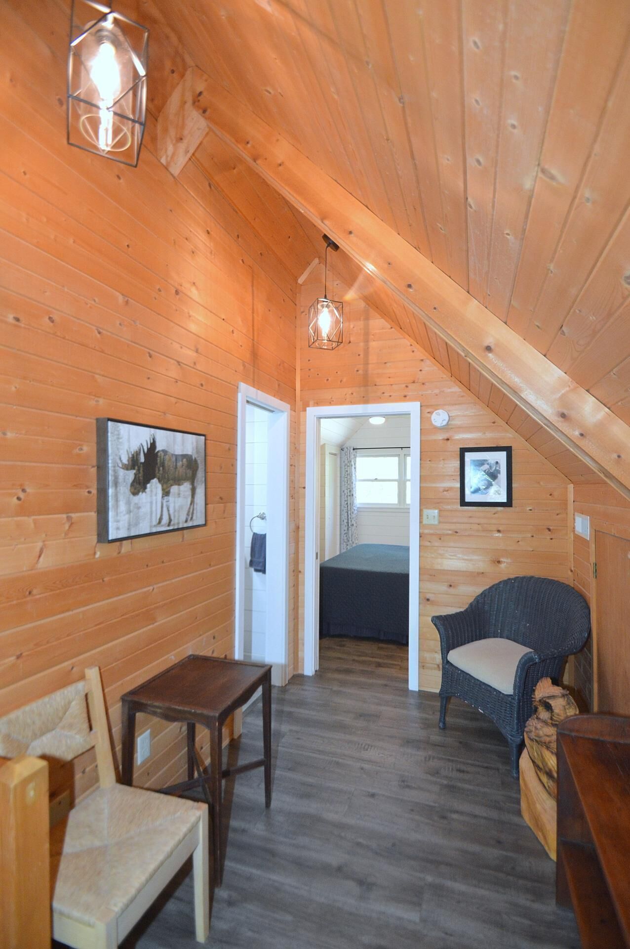 A cozy wooden cabin with a loft bedroom, a dining area, and a seating space.