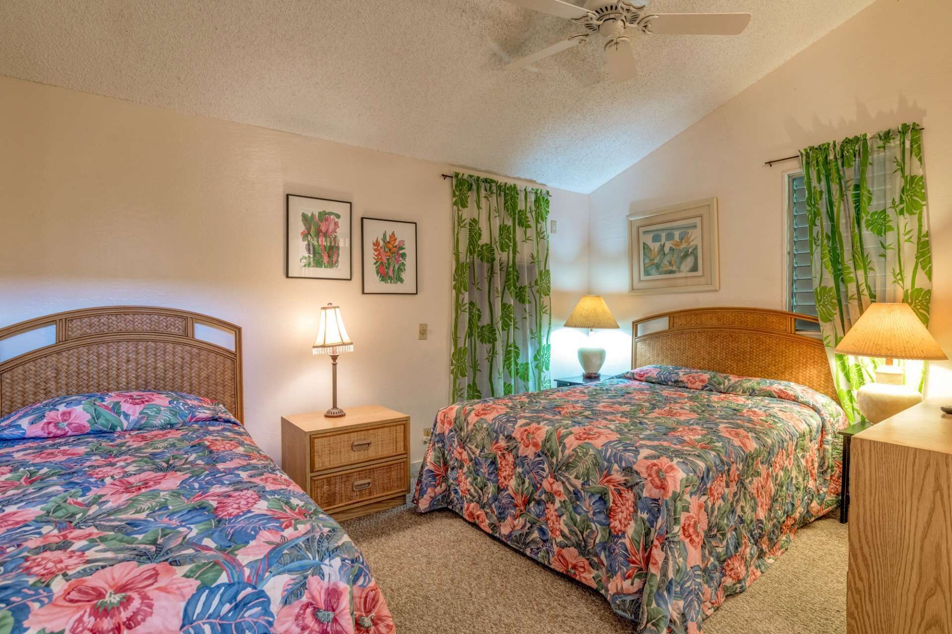 A bedroom with two beds, a ceiling fan, and floral curtains.