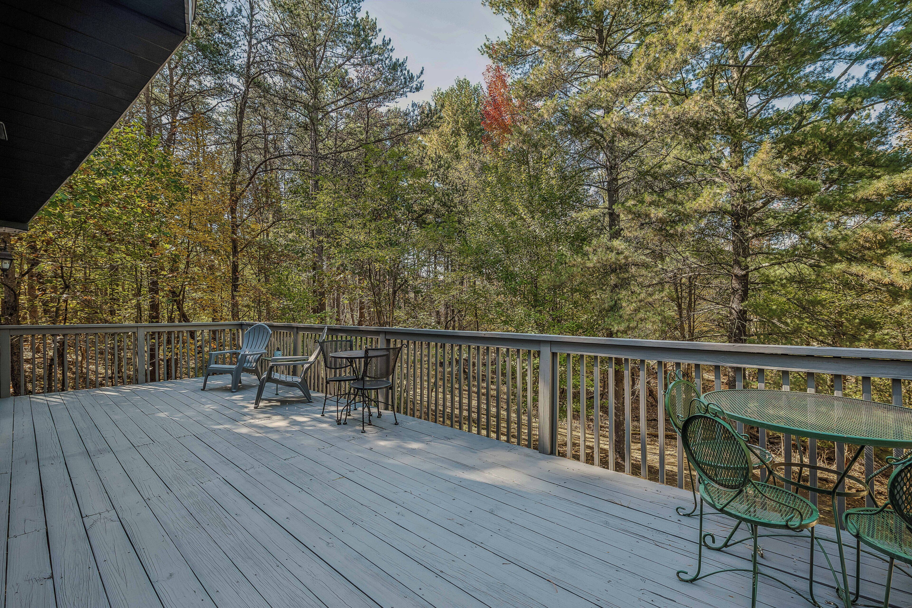 Una terraza de madera con mobiliario exterior y vista a un bosque.