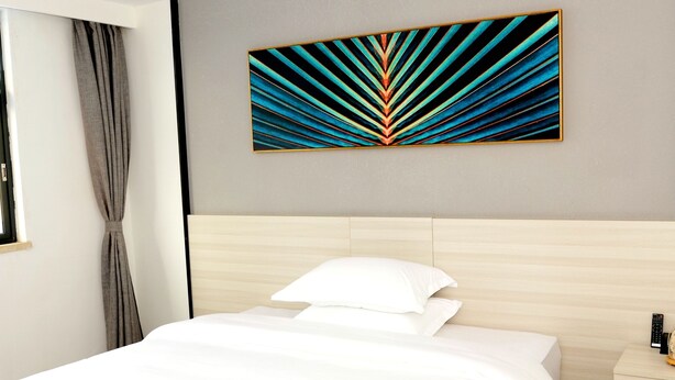 A hotel room with a bed, a nightstand, a painting, and a window with curtains.