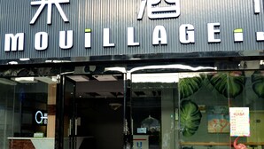A storefront with a sign reading "MOUILLAGE" and a red mat at the entrance.