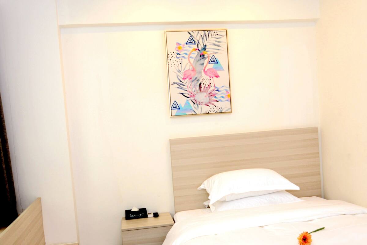 Une chambre d’hôtel avec un lit, une table de chevet, une petite table et un tableau accroché au mur.