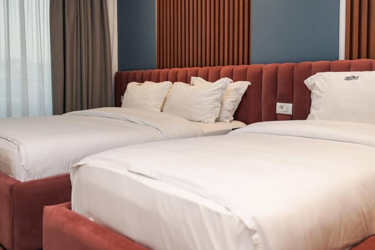 A hotel room with two beds, each with white bedding and a red headboard.