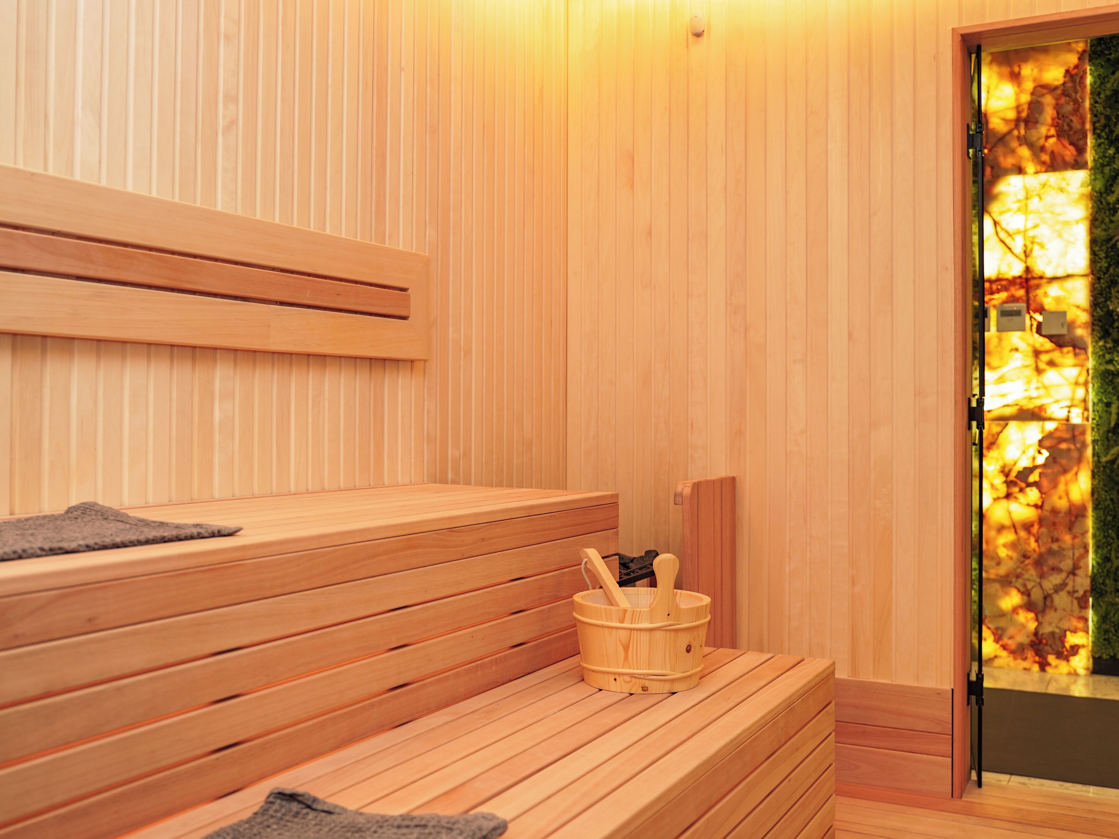 A wooden sauna with benches and a wooden bucket with a ladle.
