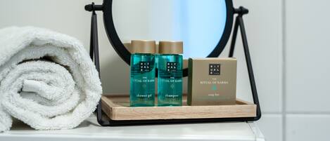A bathroom vanity with a mirror, a towel, and a tray holding a shower gel bottle, a shampoo bottle, and a soap bar.