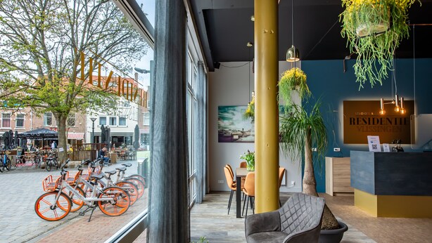 Decoração moderna com balcão de recepção, área de estar e bicicletas na frente.