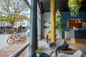 Un intérieur moderne avec un comptoir d’accueil, un espace détente et des vélos à l’extérieur.