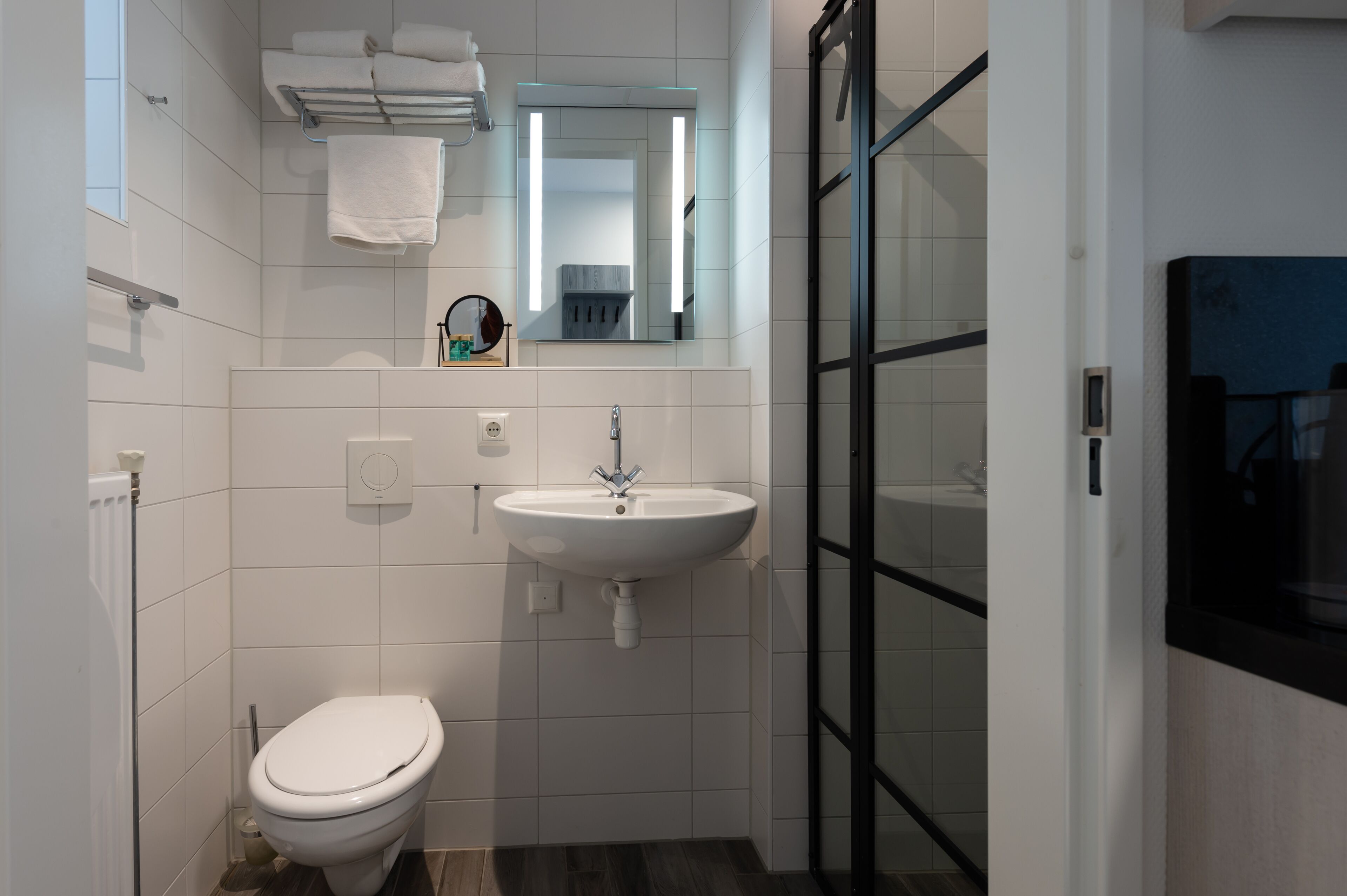 Un baño moderno con un lavamanos blanco, inodoro y cabina de ducha de vidrio.