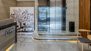 A modern lobby with a reception desk, a wall mural, a marble floor, and a lift.